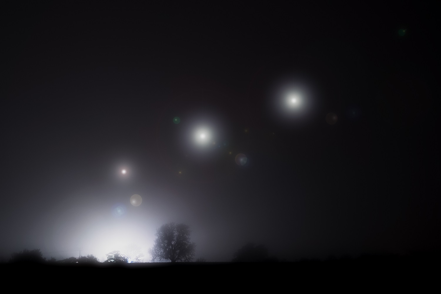 Glowing alien UFO lights floating in the sky.