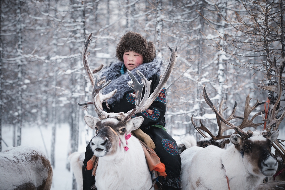 Little boy riding a reindeer
