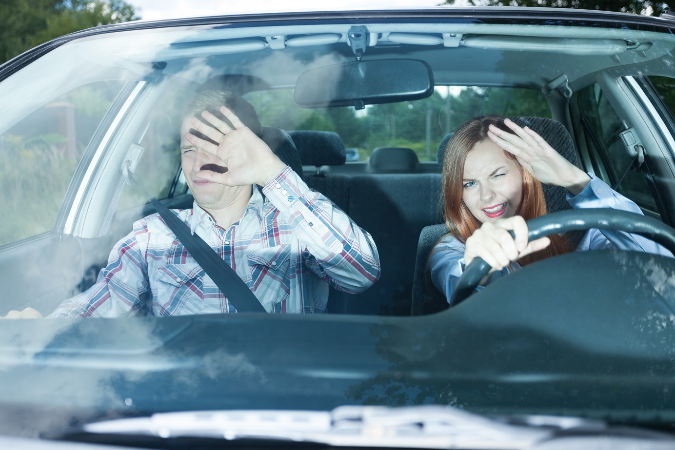 Young couple in car blinded by high beam lights.