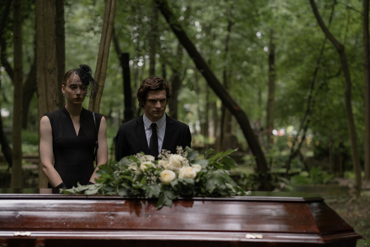 Man and woman standing beside the wooden coffin.