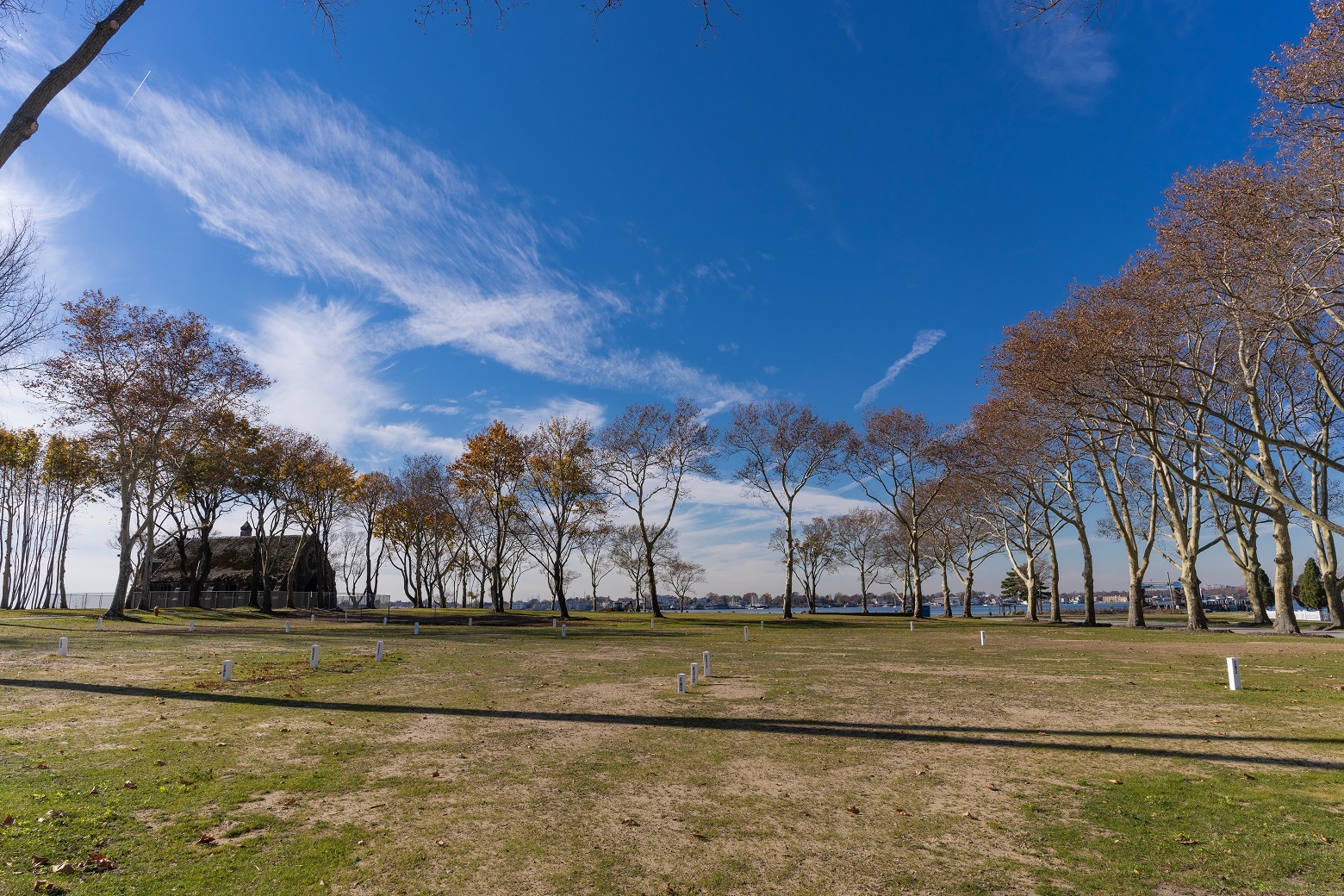 View of white marks of burial plots with ruins of chapel in the background on Hart Island  - 2023
