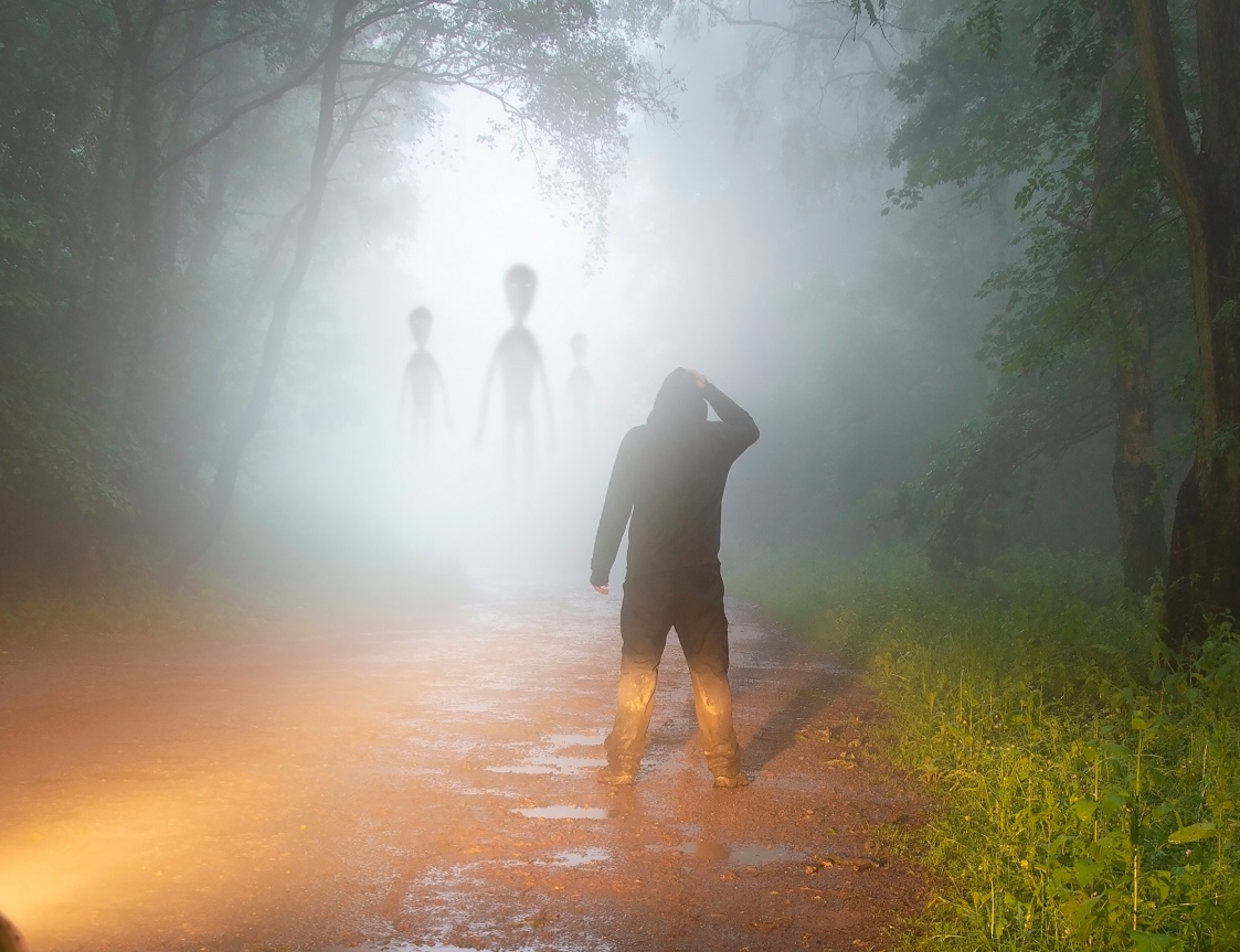 A science fiction concept of a man looking at aliens coming out the mist.