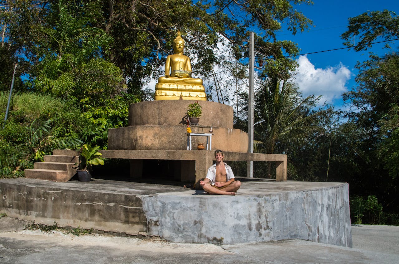 A man is sitting near the buddha.