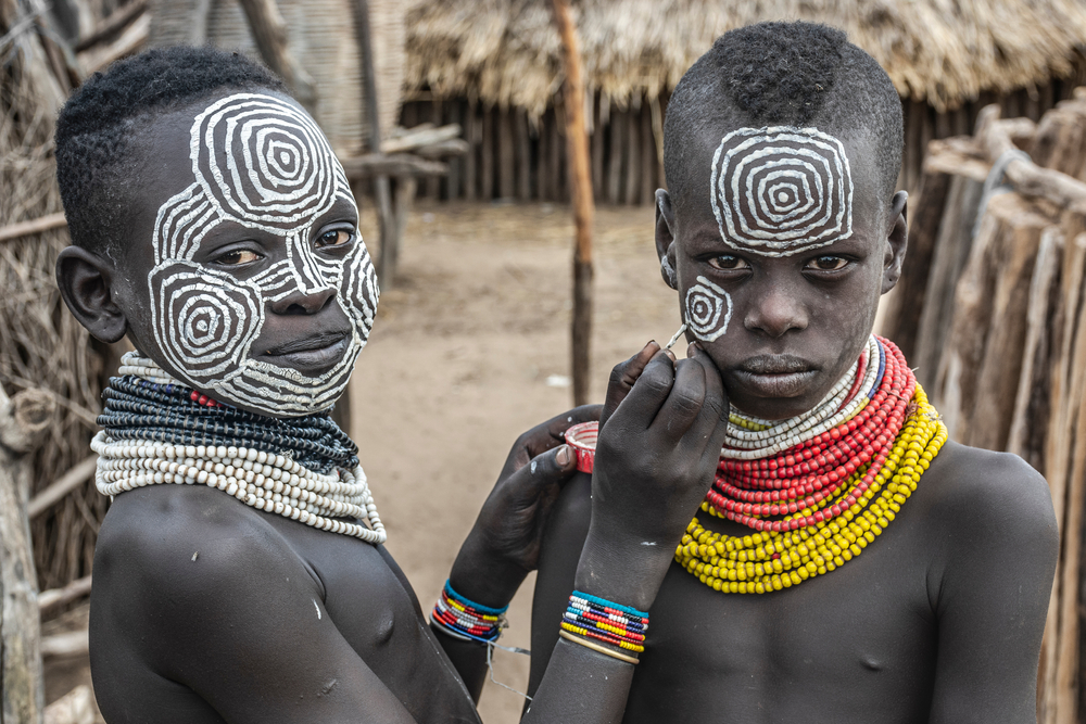 Portrait of a boy from the Karo tribe doing a traditional painting