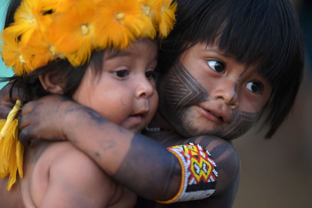 A young boy from the Kayapo tribe hugs a young girl from the Krenak tribe