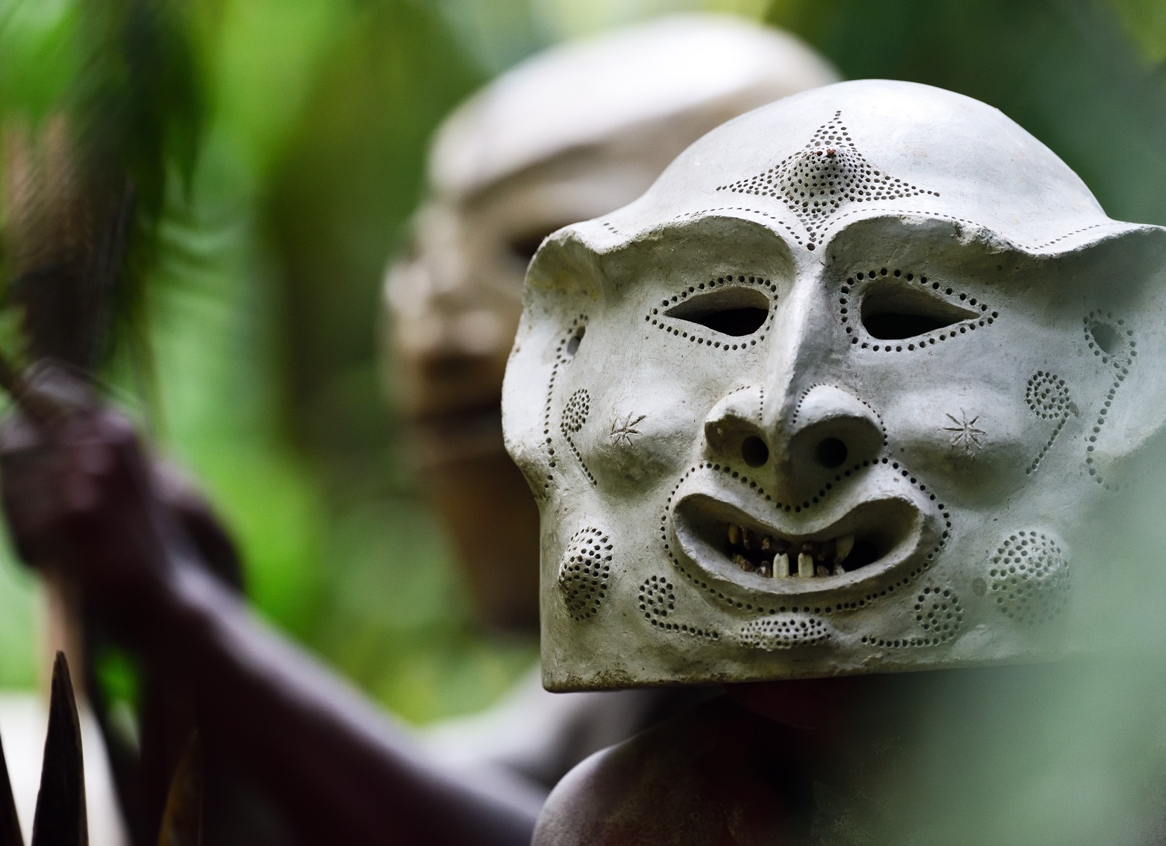 A Asaro Mudman wearing the traditional mask/helmet, at a ceremony in the forest.