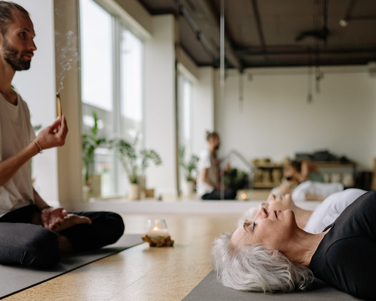 Man sitting in the lotus position conducting a yoga class.
