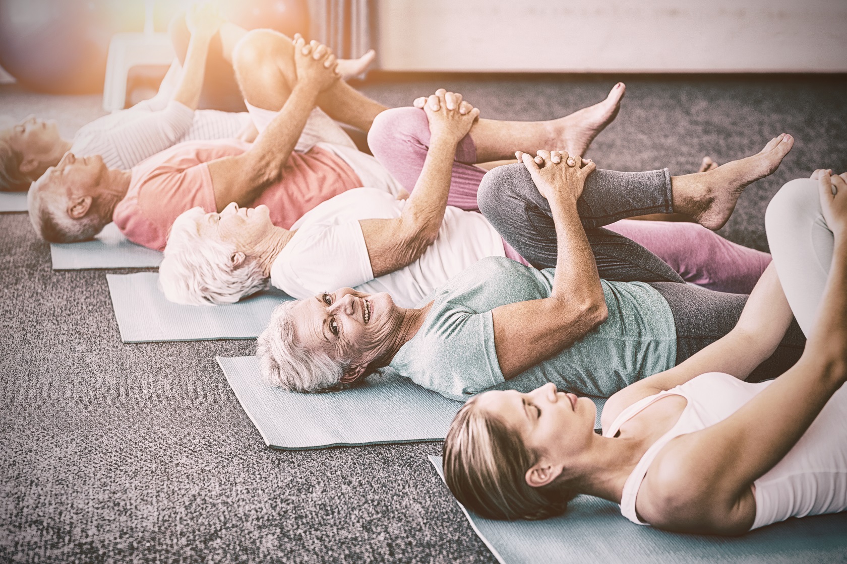 Instructor performing yoga with seniors during sports class.