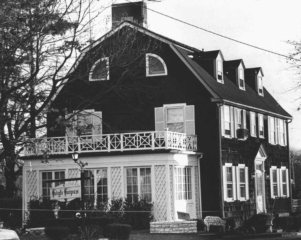 A large Dutch Colonial house situated in a suburban neighborhood in Amityville