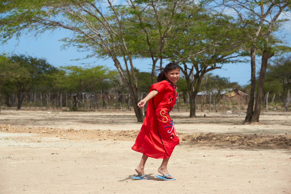 Teenage woman running happily in a desert and wearing a typical Wayuu Indian dress