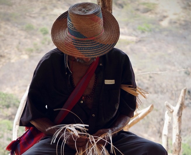 Wayuu artisan working an wearing a traditional tribe hat