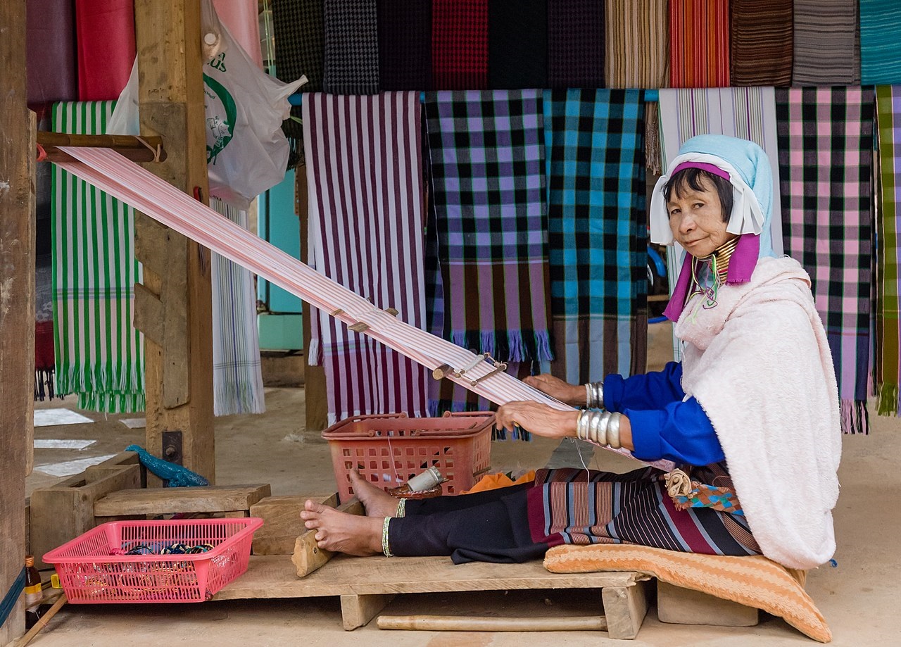 Woman of the Kayan people with decorative neck rings working at her loom. - 2009