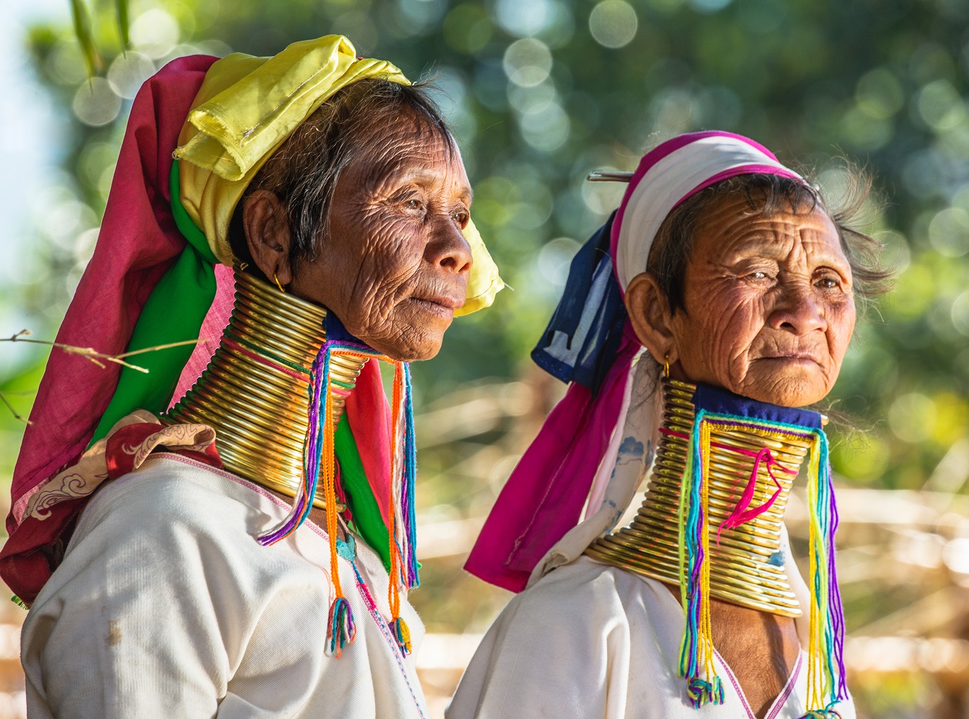 Two Padaung women in traditional dress and with metal rings around their neck - 2019, Myanmar.