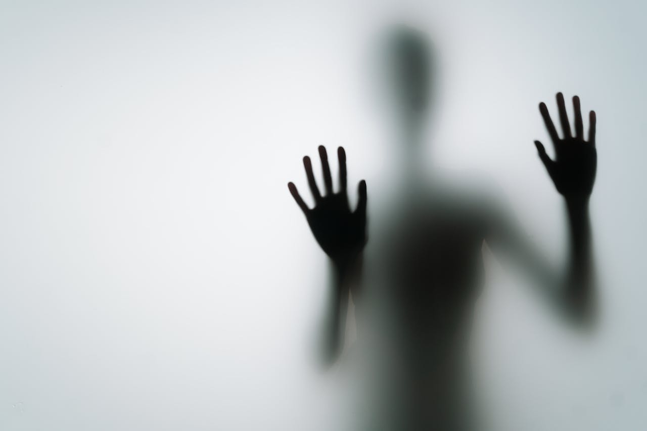 Silhouette of person with hands on glass