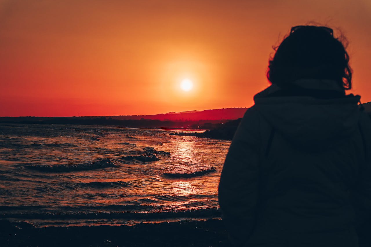 Silhouette of Person Standing on Shore during Sunset