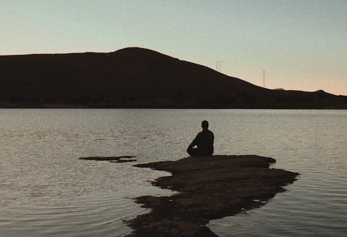 Man sitting on sea rock.
