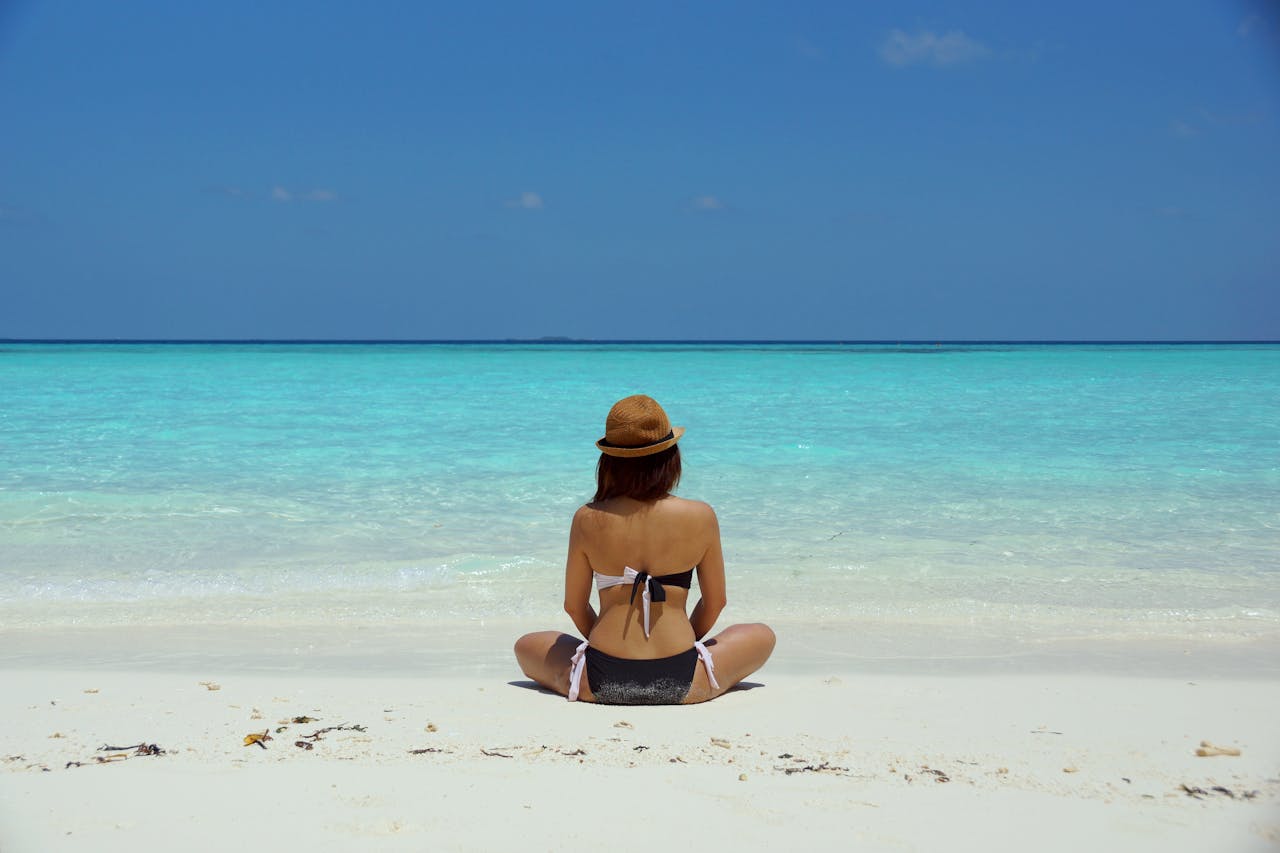 Woman is sitting on white sand.