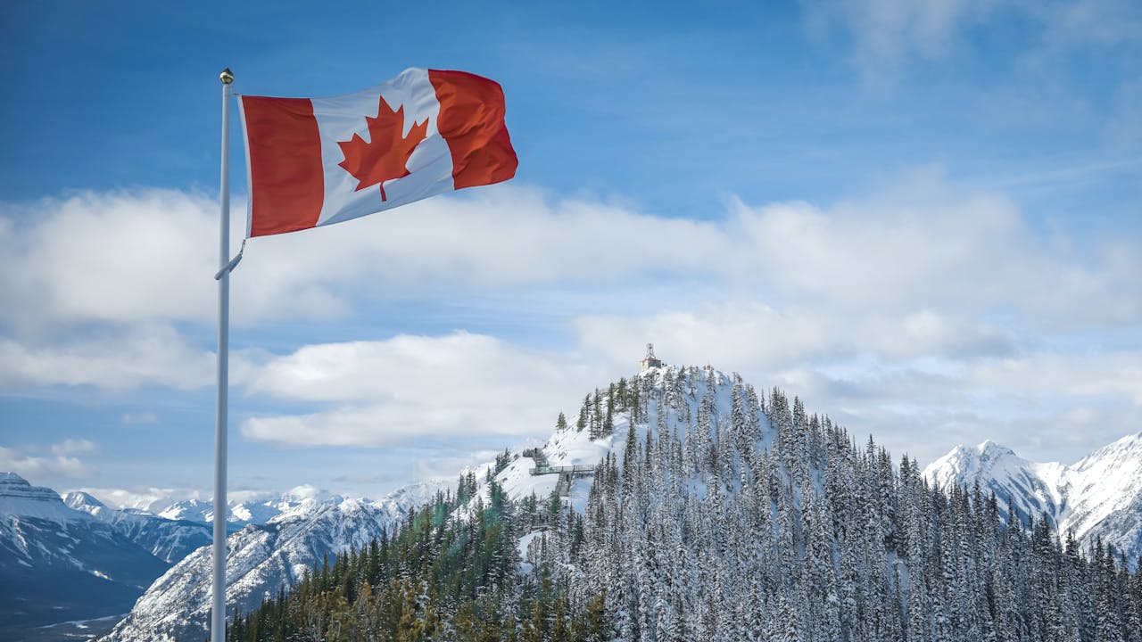 Landscape Photo of Snowy Mountains with the Canada Flag in front