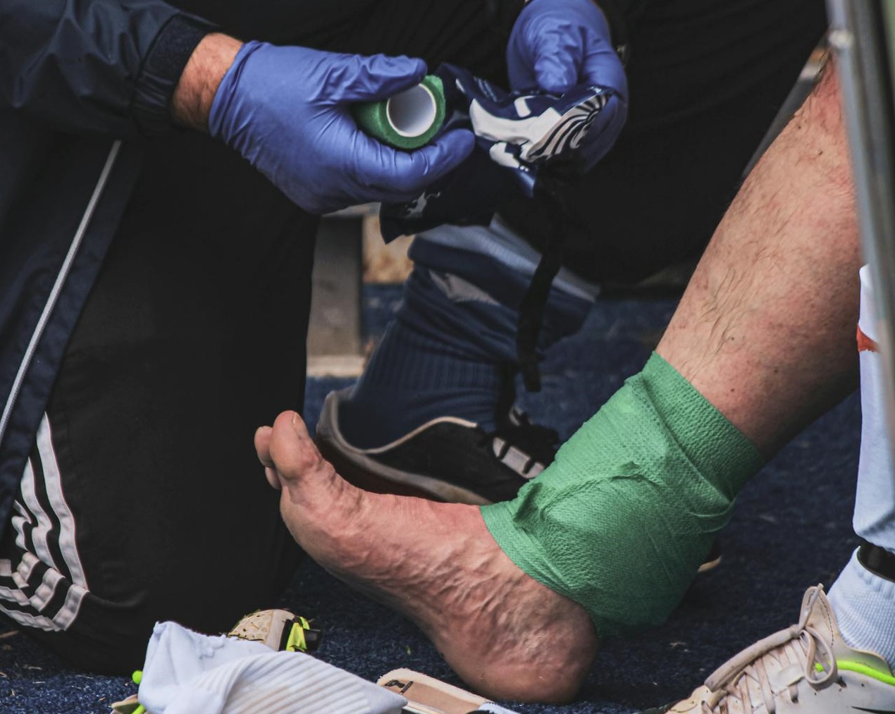 Man helping another man with leg injury.