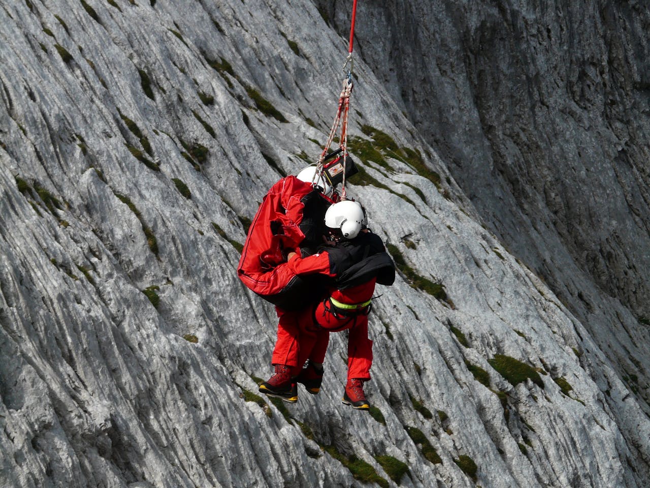 Two People Rappelling Near Grey Rocks- airlift