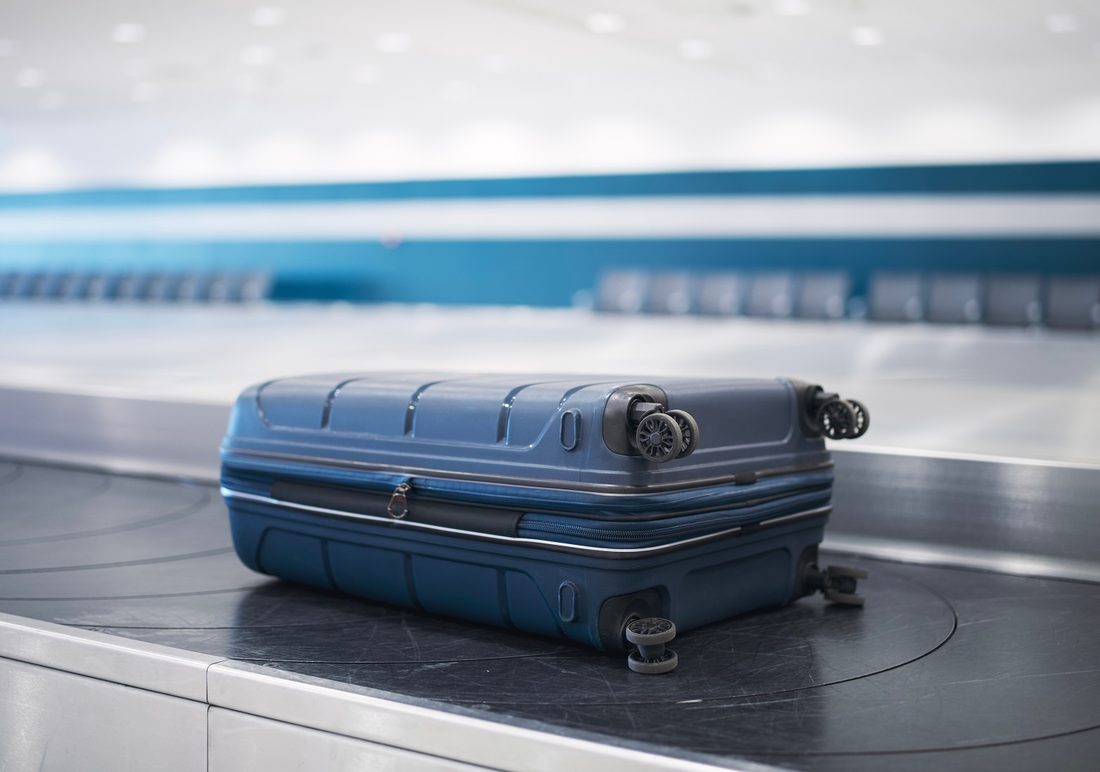 Blue suitcase on baggage claim in airport terminal.