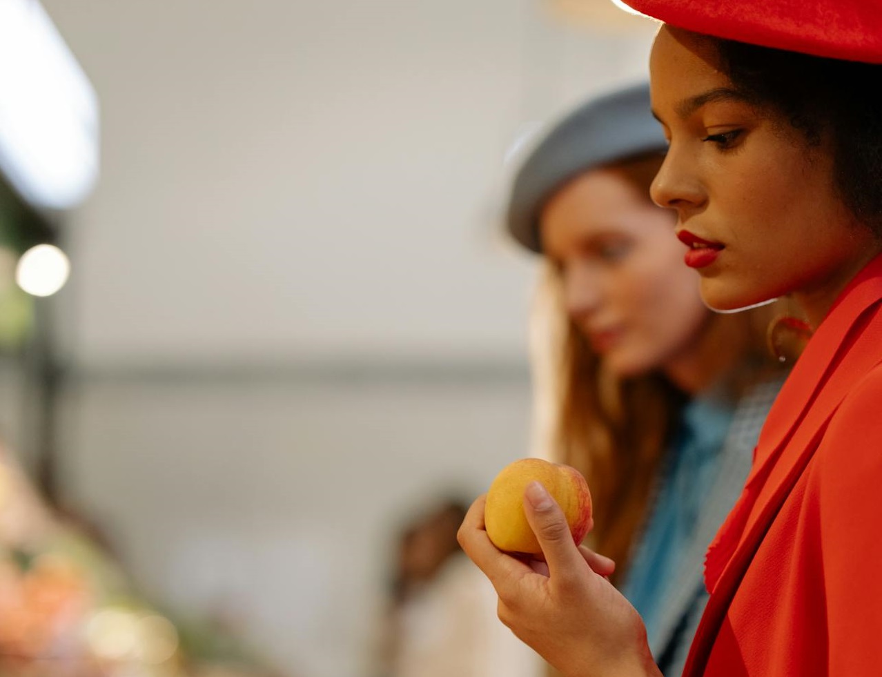 Woman in red coat holding a peach.