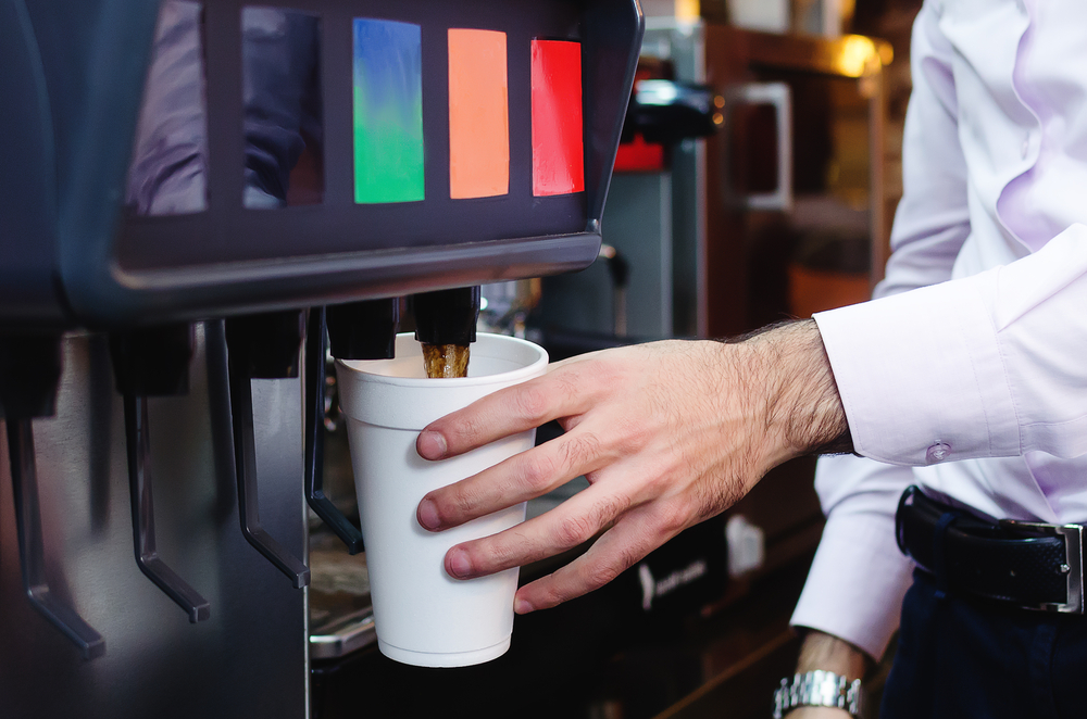 man pours a fizzy drink into a paper glass