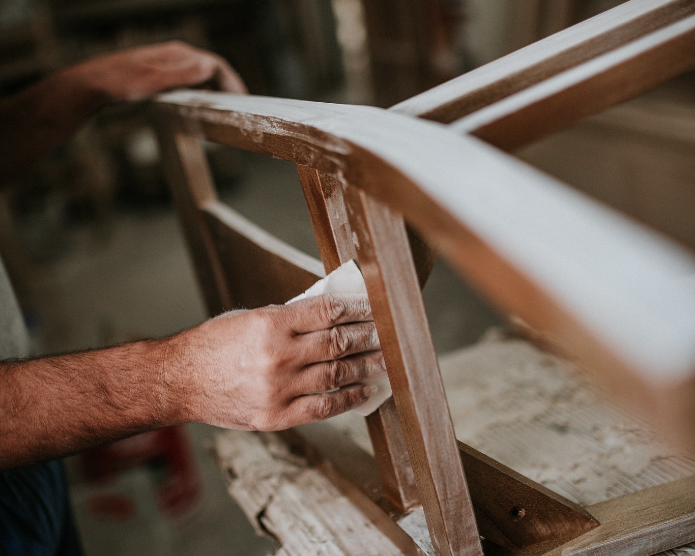 Carpenter sanding a chair with sandpaper in a small workshop