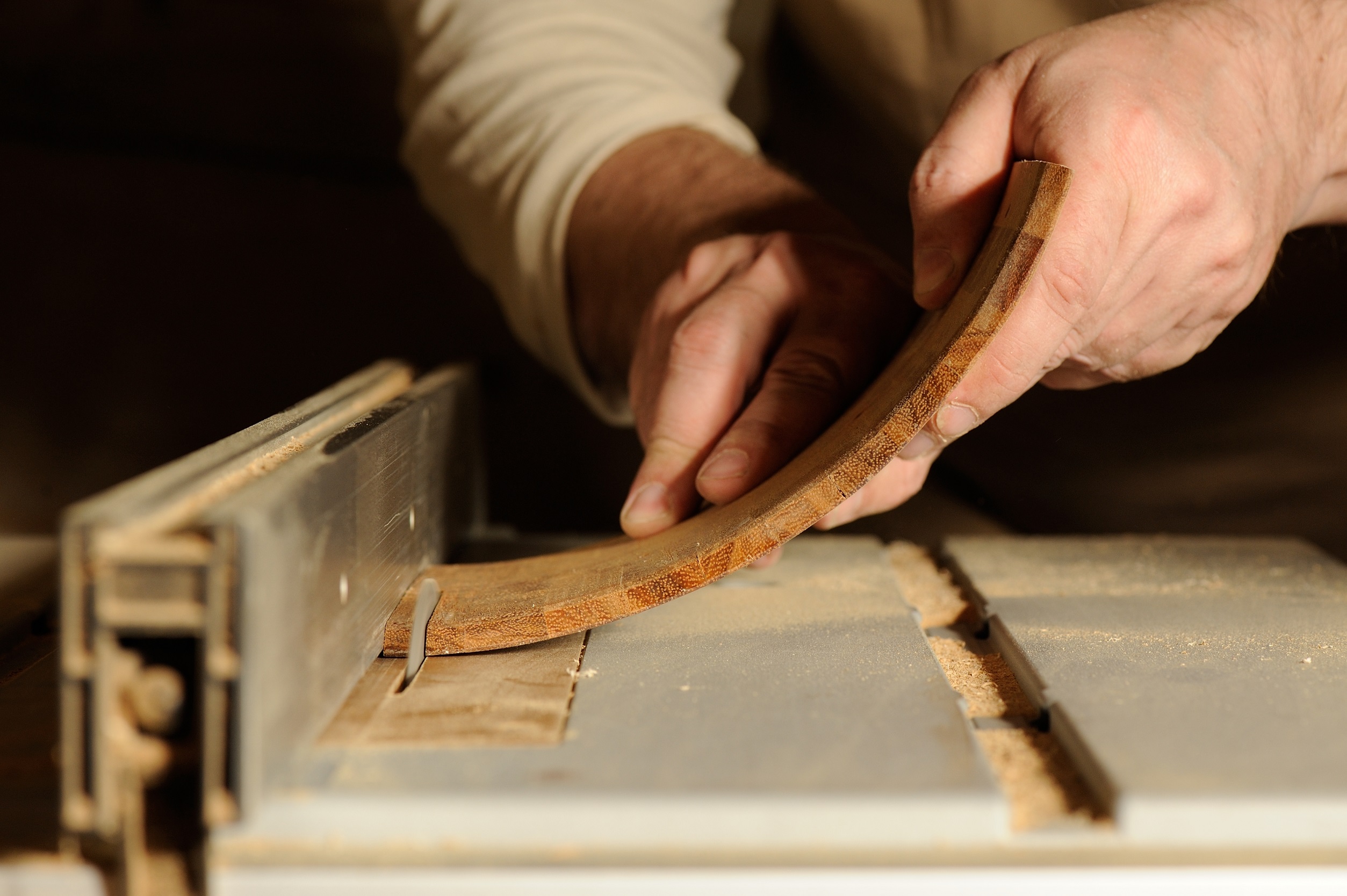 Carpenter cutting curved piece of wood by wood cutter