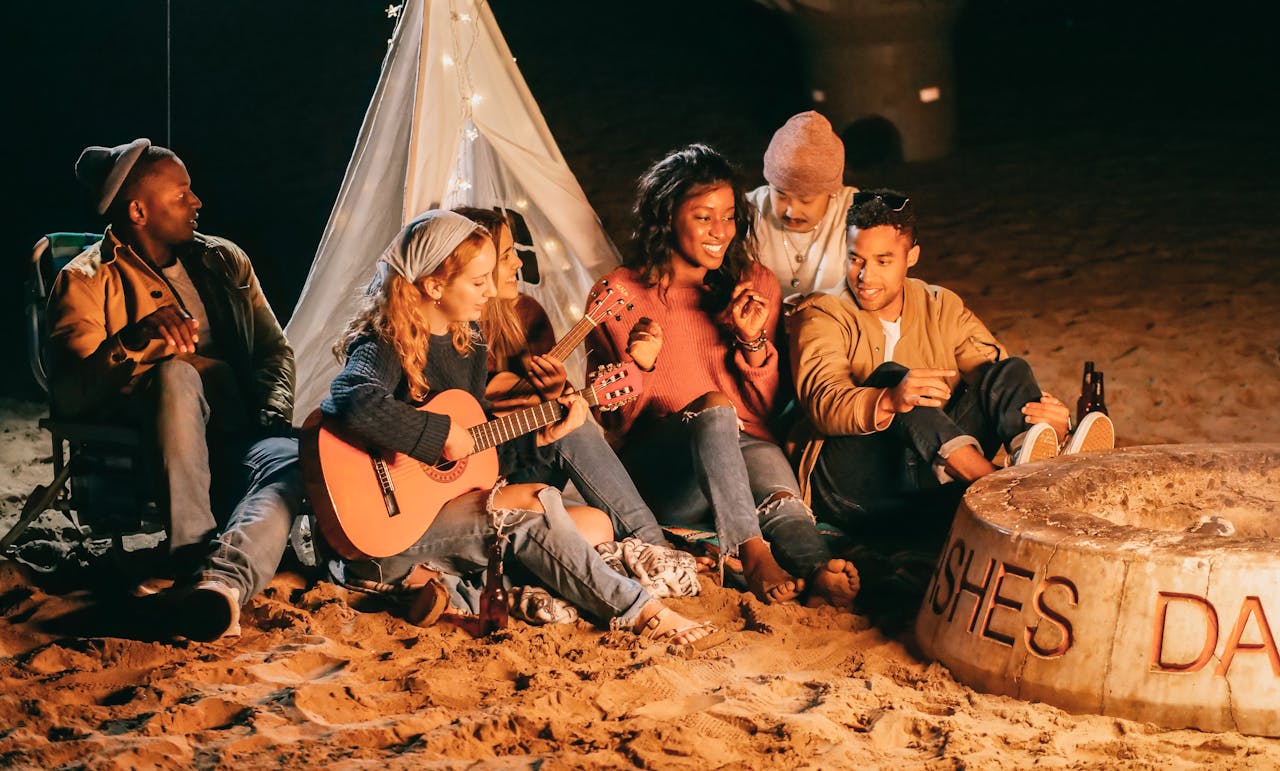 Group of Friends Sitting on Beach Sand in front of tent
