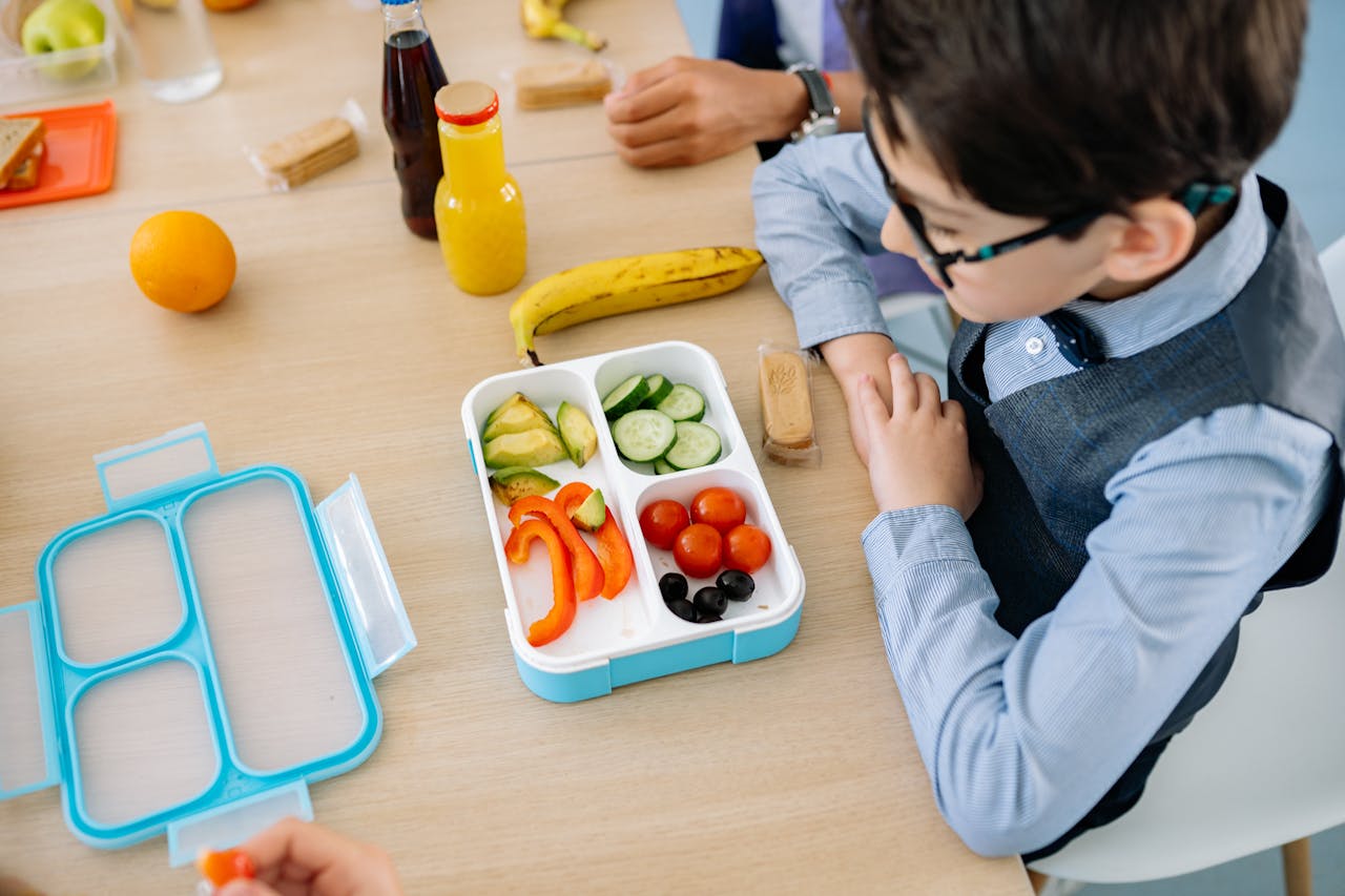 Boy Sitting on Chair in Front of Table With Lunch Box