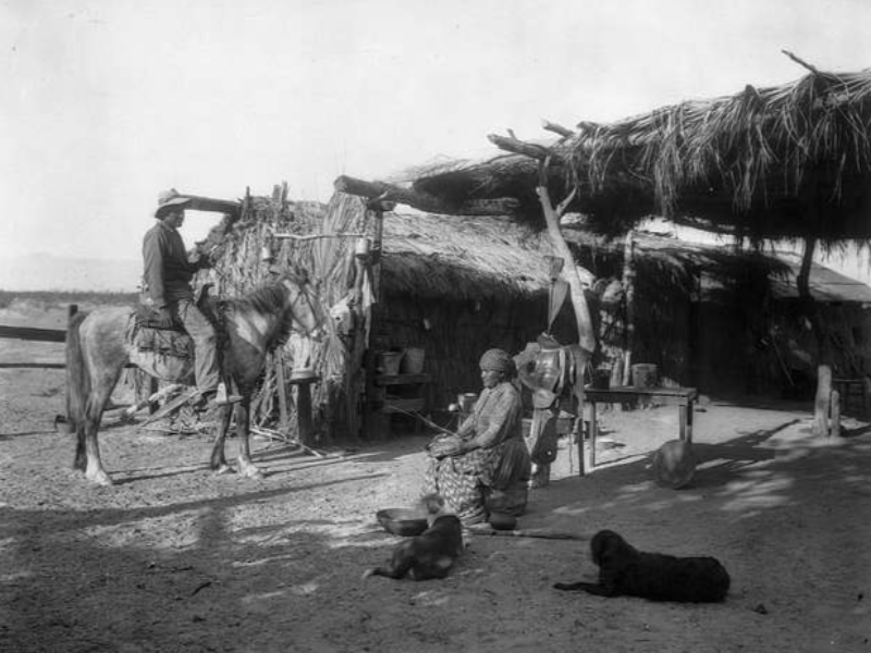 Photograph of cahuilla Indians, Husband and wife, outside of their grass home