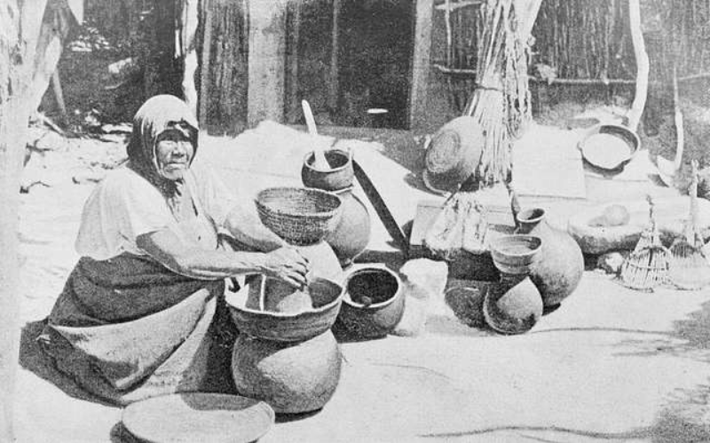 Cahuilla Woman sitting in front of big clay bowls