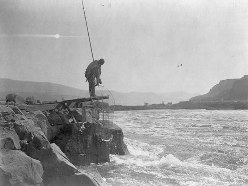 indian man standing on a big rock and fishing