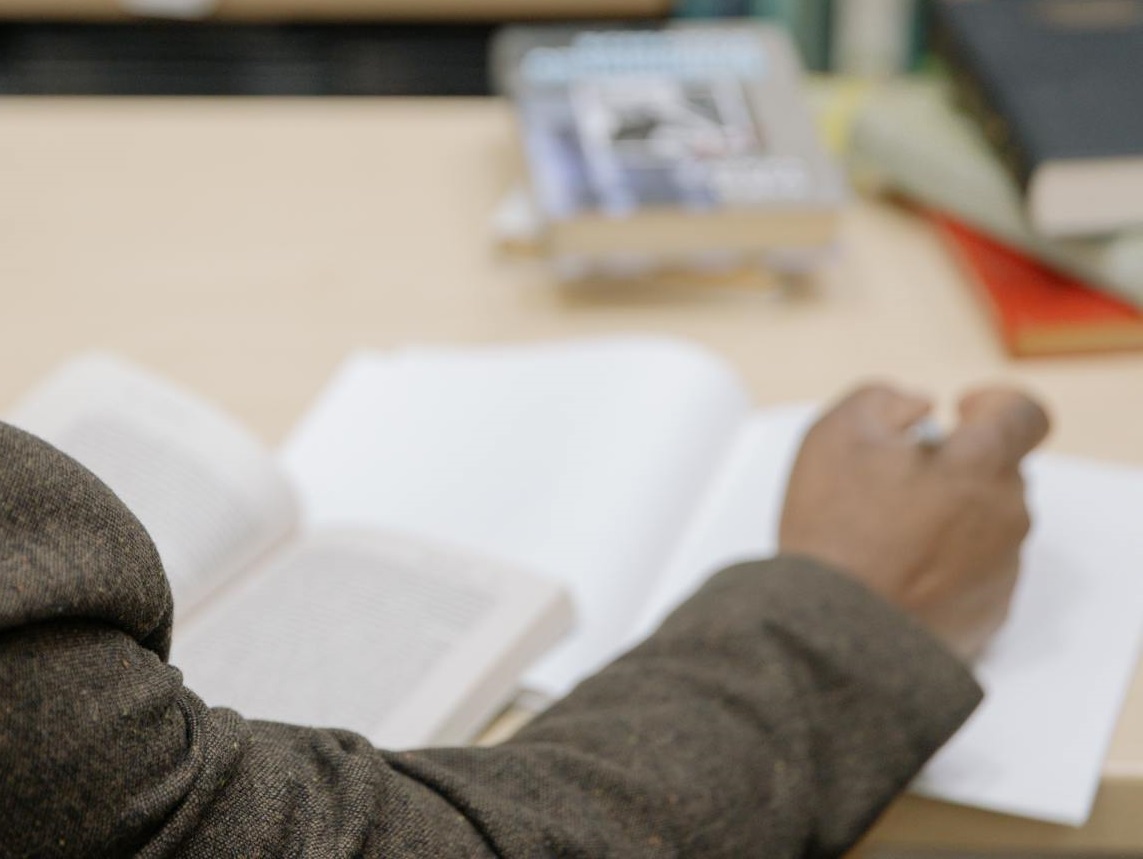 Man Reading and Writing Inside a Library.