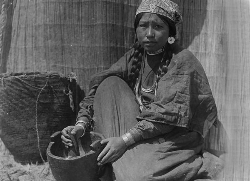 Indian woman seating with mortar and pestle.
