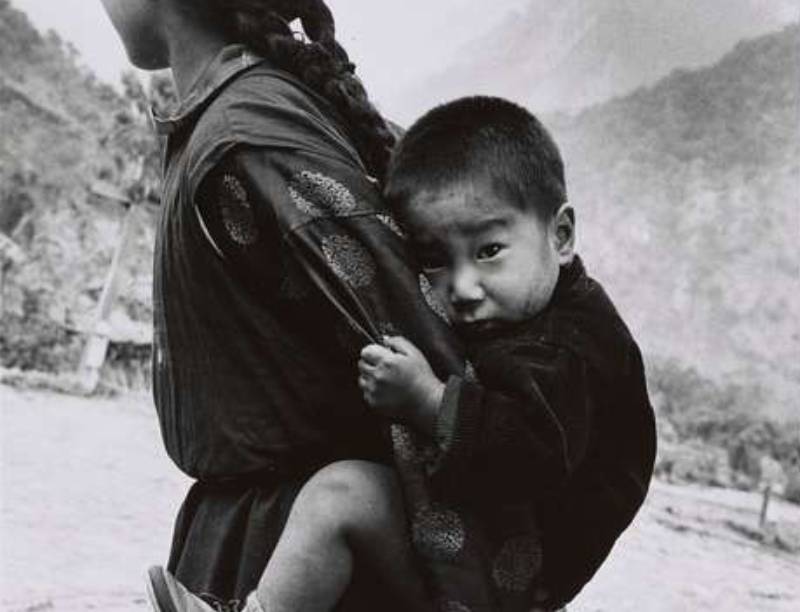 Young Woman With A Small Child On Her Back