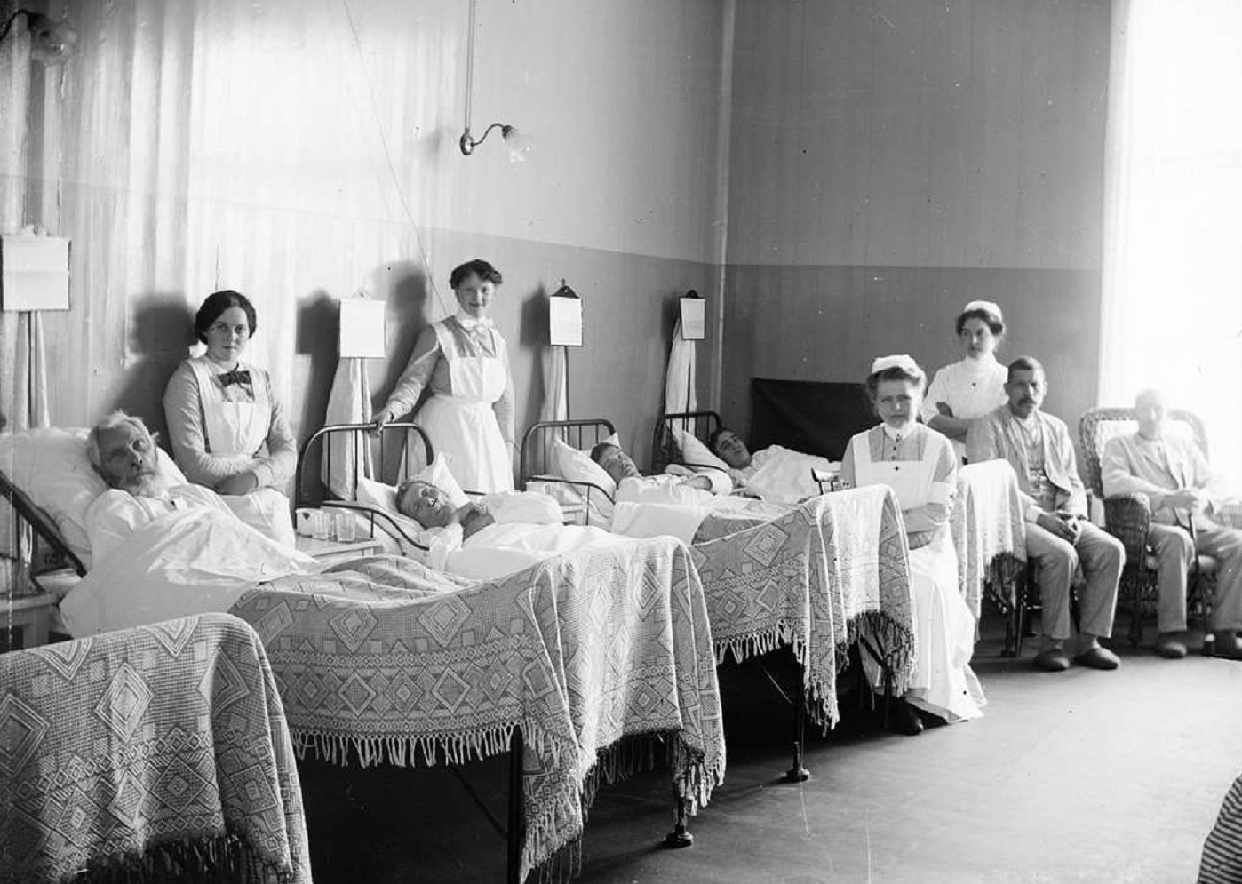 People in hospital bed next to nurses