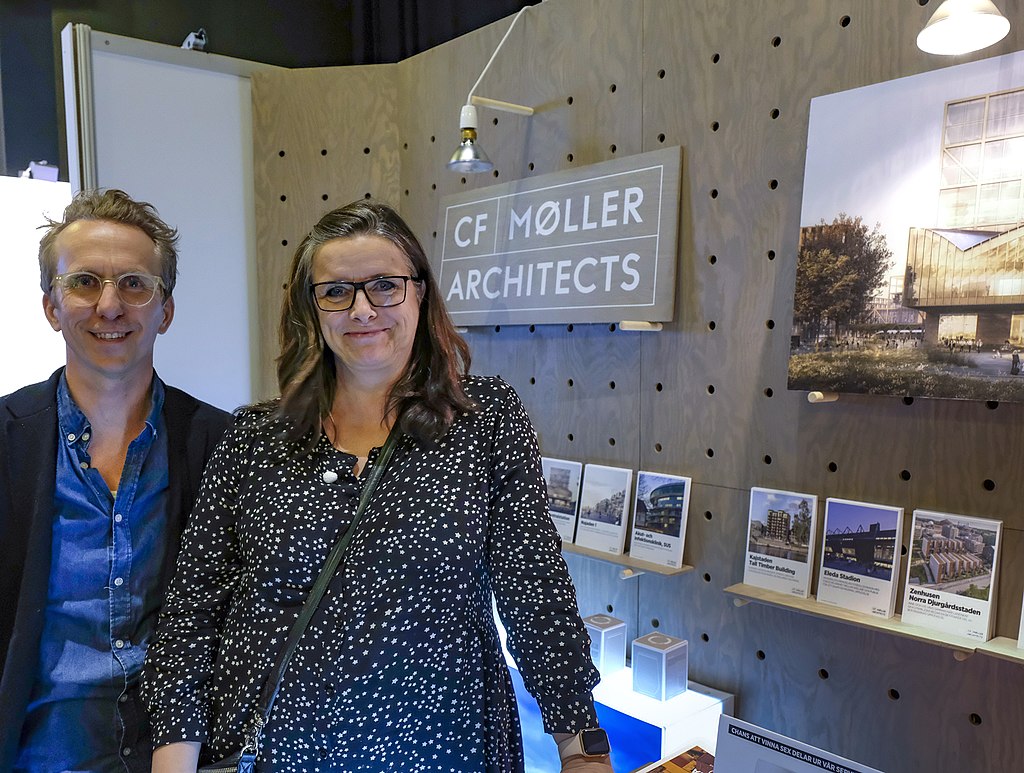 Image of two people standing in front of company logo