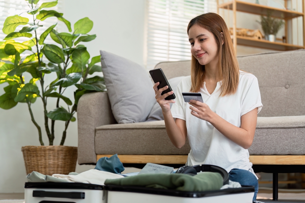 Happy young woman with credit card booking vacation