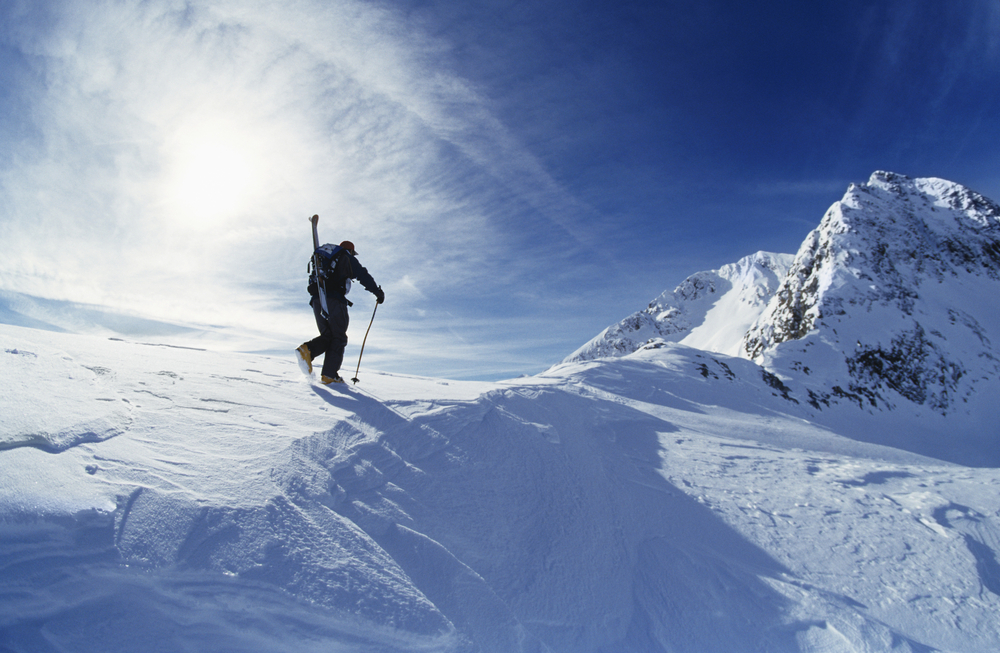 Rear view of skier hiking to mountain summit
