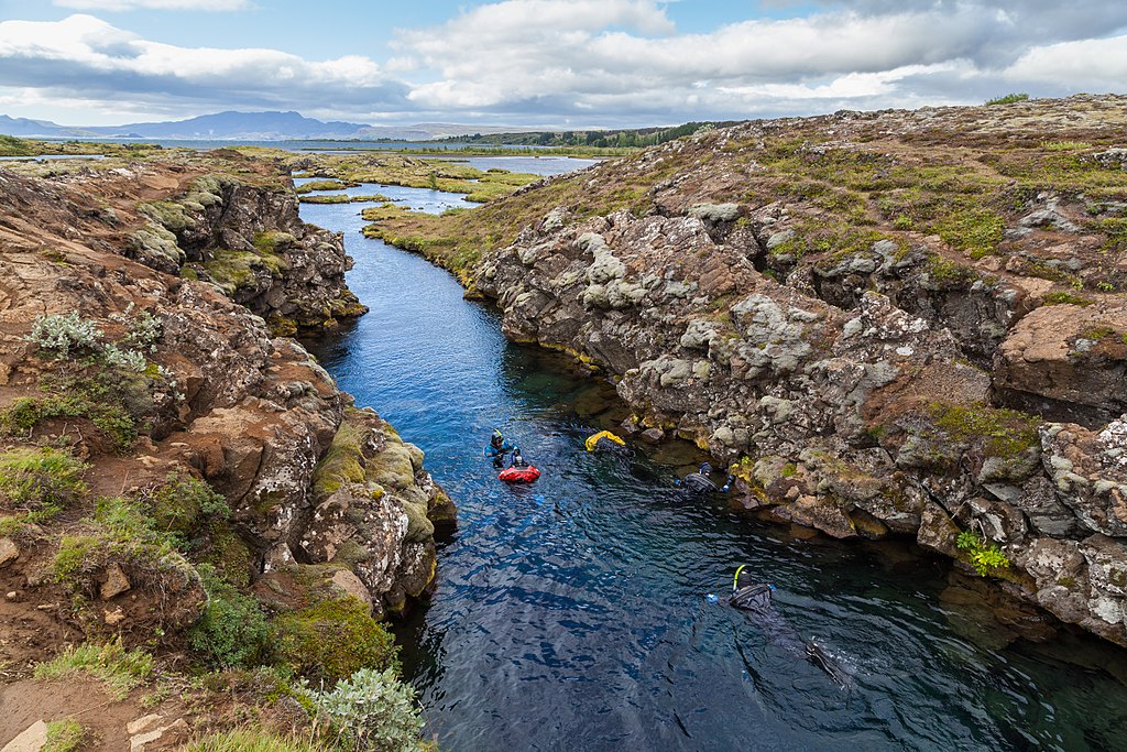 People Snorkeling at Silfra rift with cloudy sky in the background