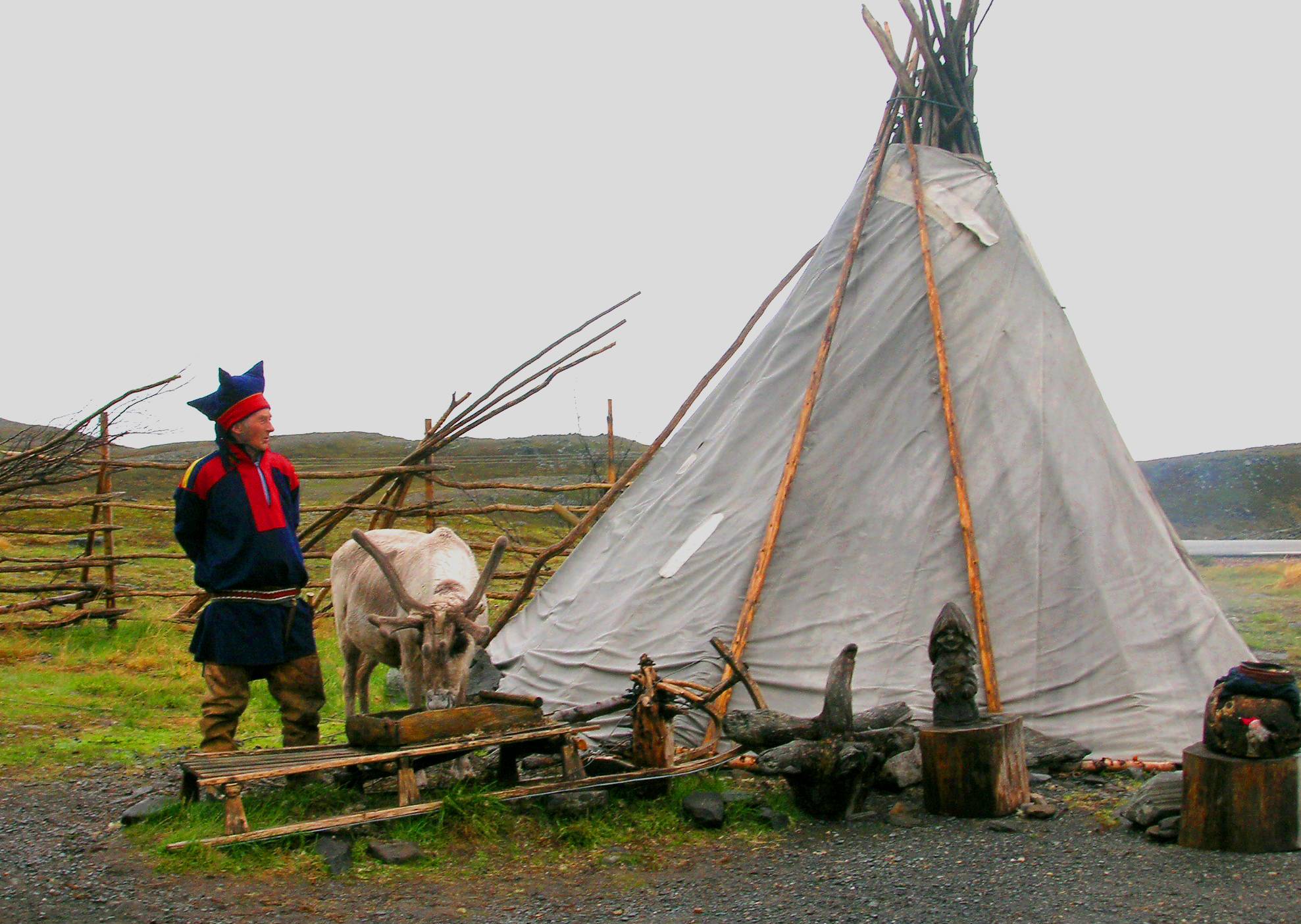 Sami men in traditional clothes next to his hut