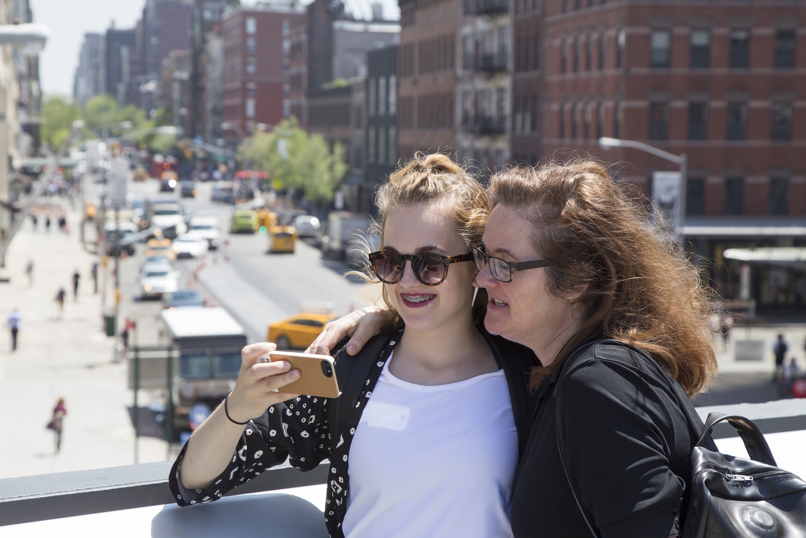 Mother and daughter watch a picture on the phone of the daughter.