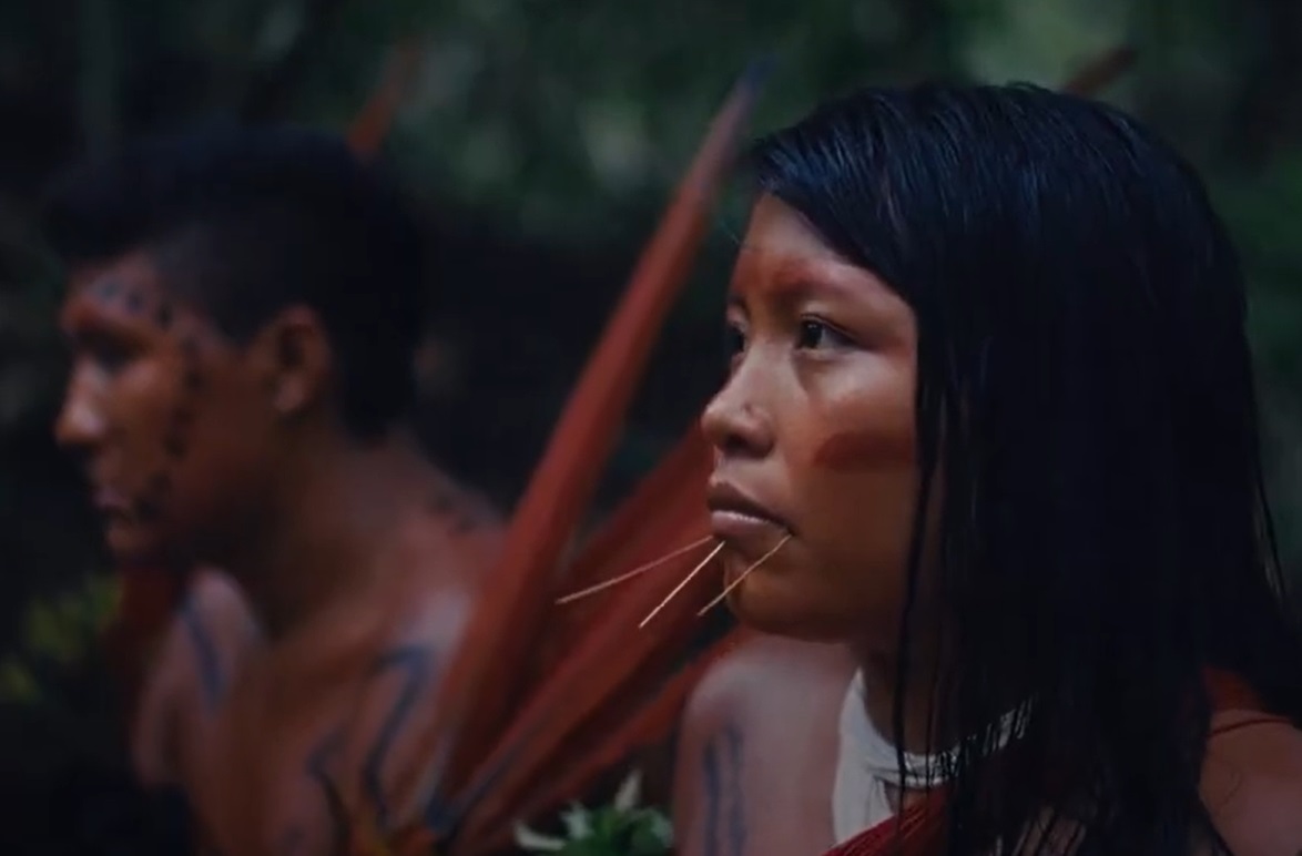 Photo of Yanomami man and woman sitting next to each other blurred background
