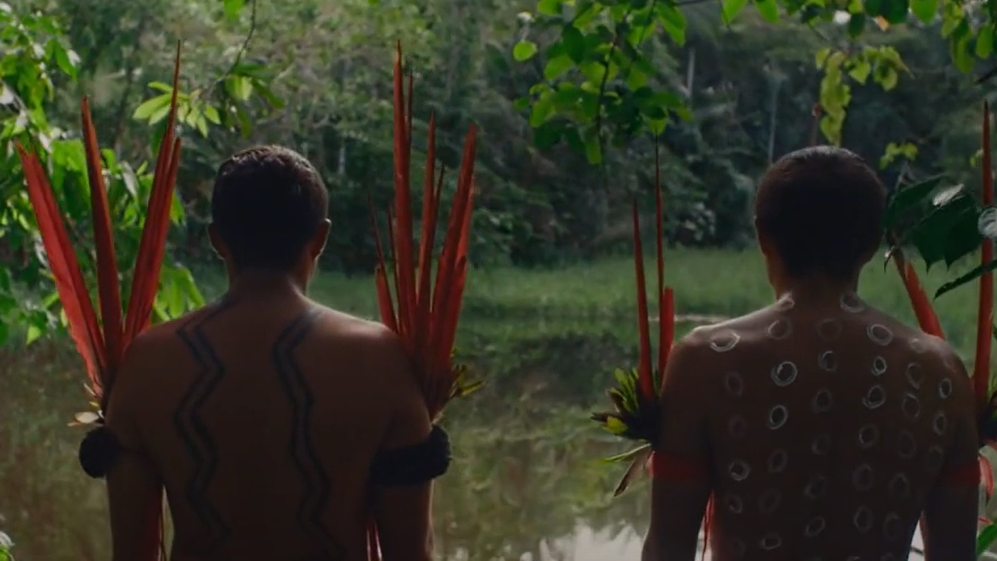 Photo of two Yanomami men standing to each other with turned backs