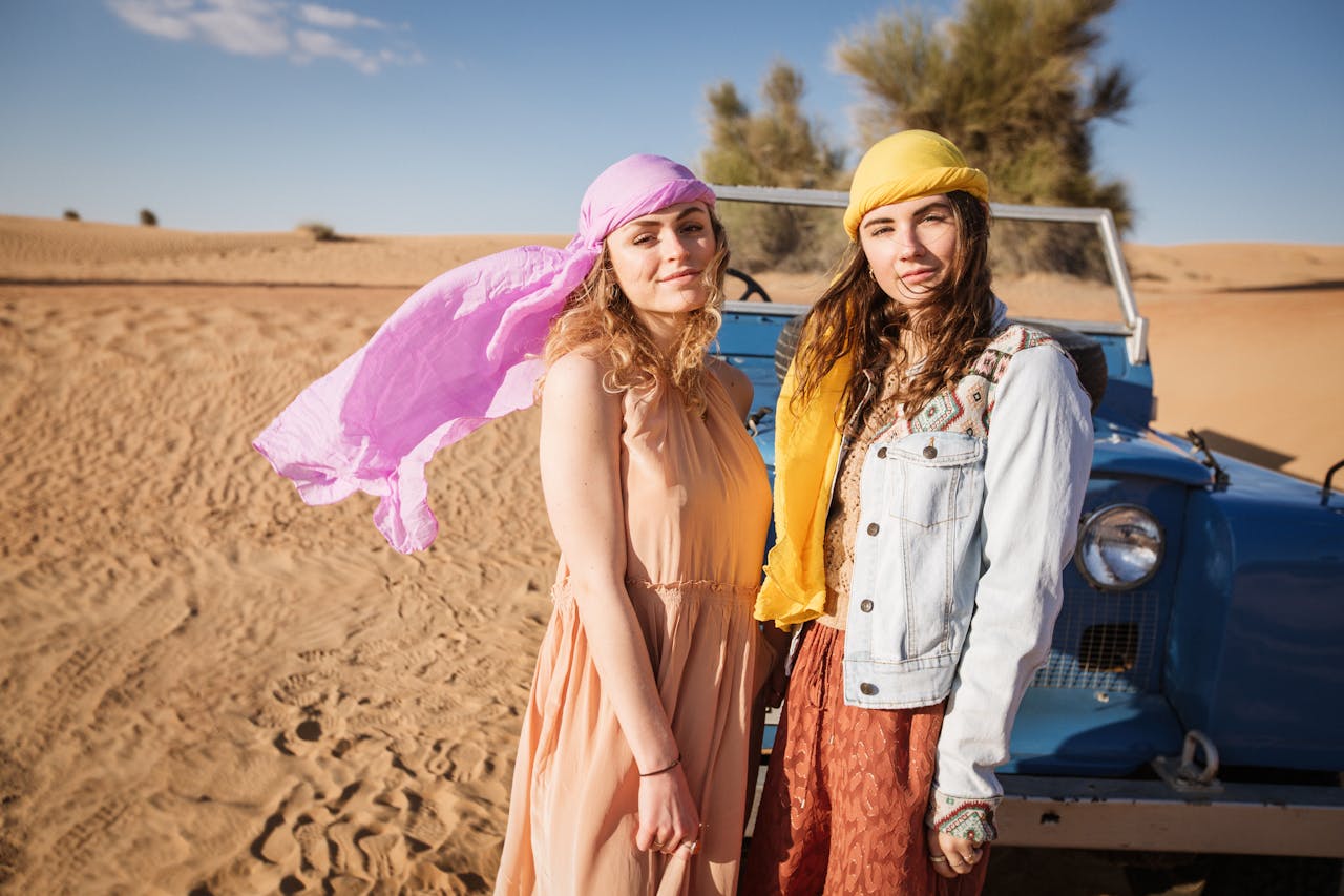 Two Women Wearing Yellow and Purple Headscarf Standing Near A Blue Land Rover