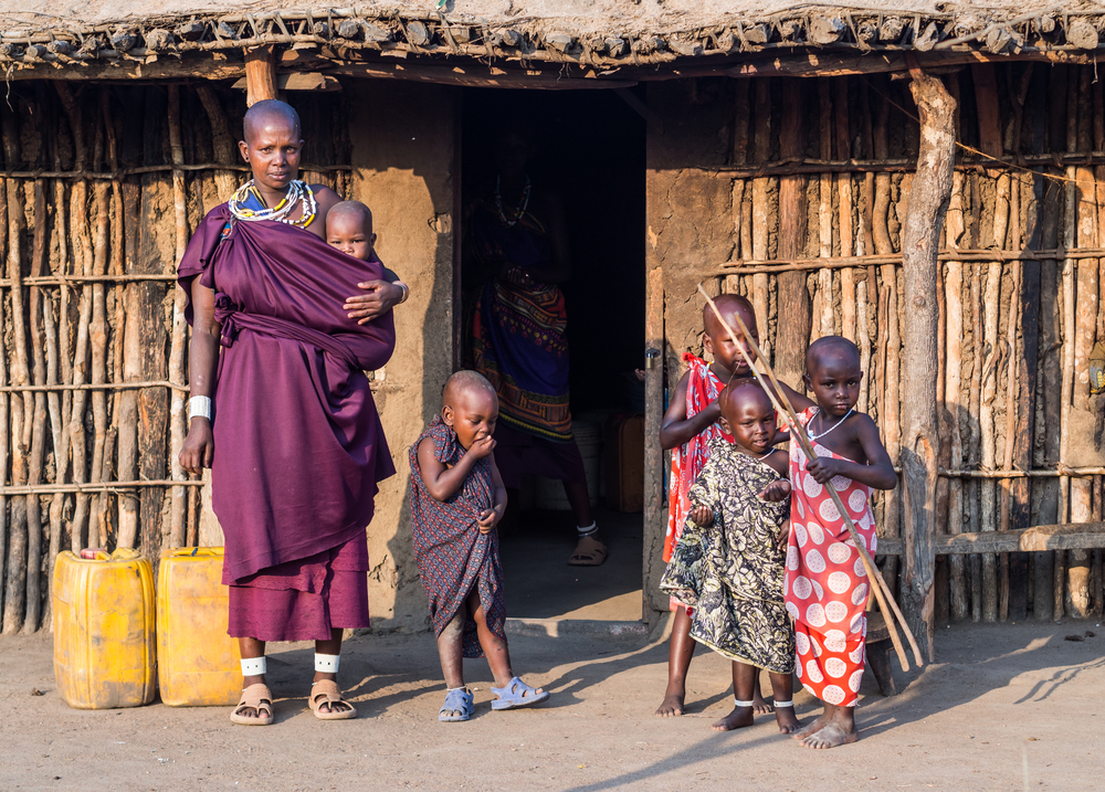 Maasai family in front of a traditional house