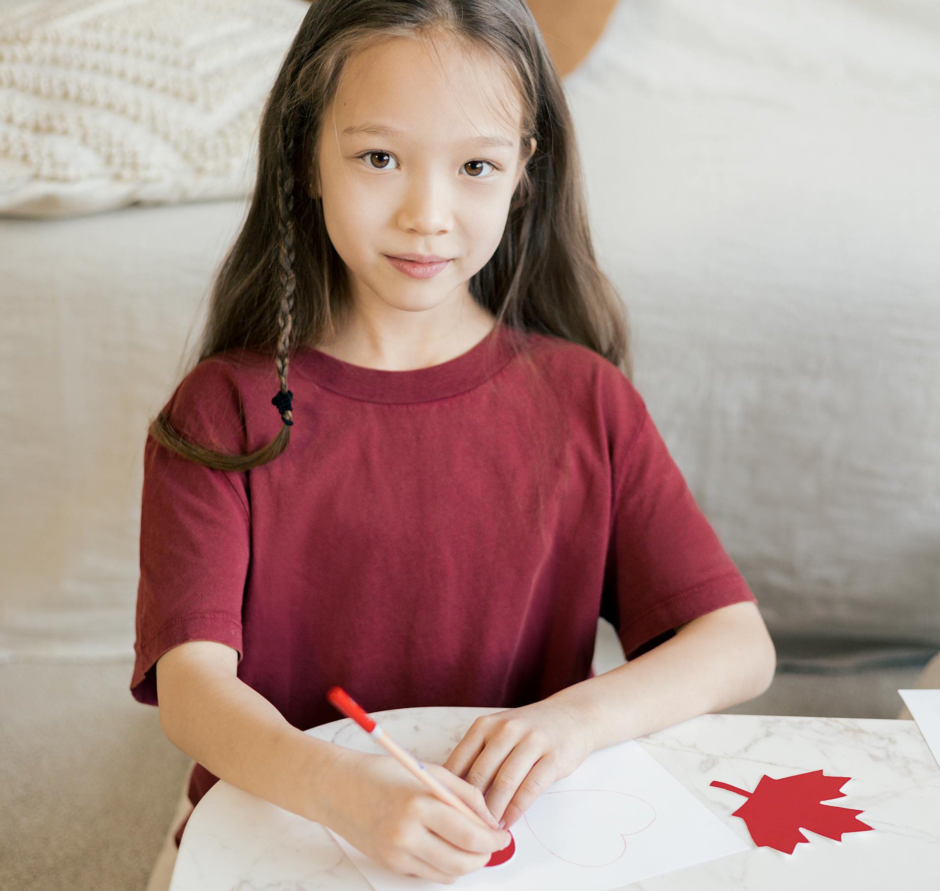 Portrait Photo of a Child in a red t-shirt drawing on a table