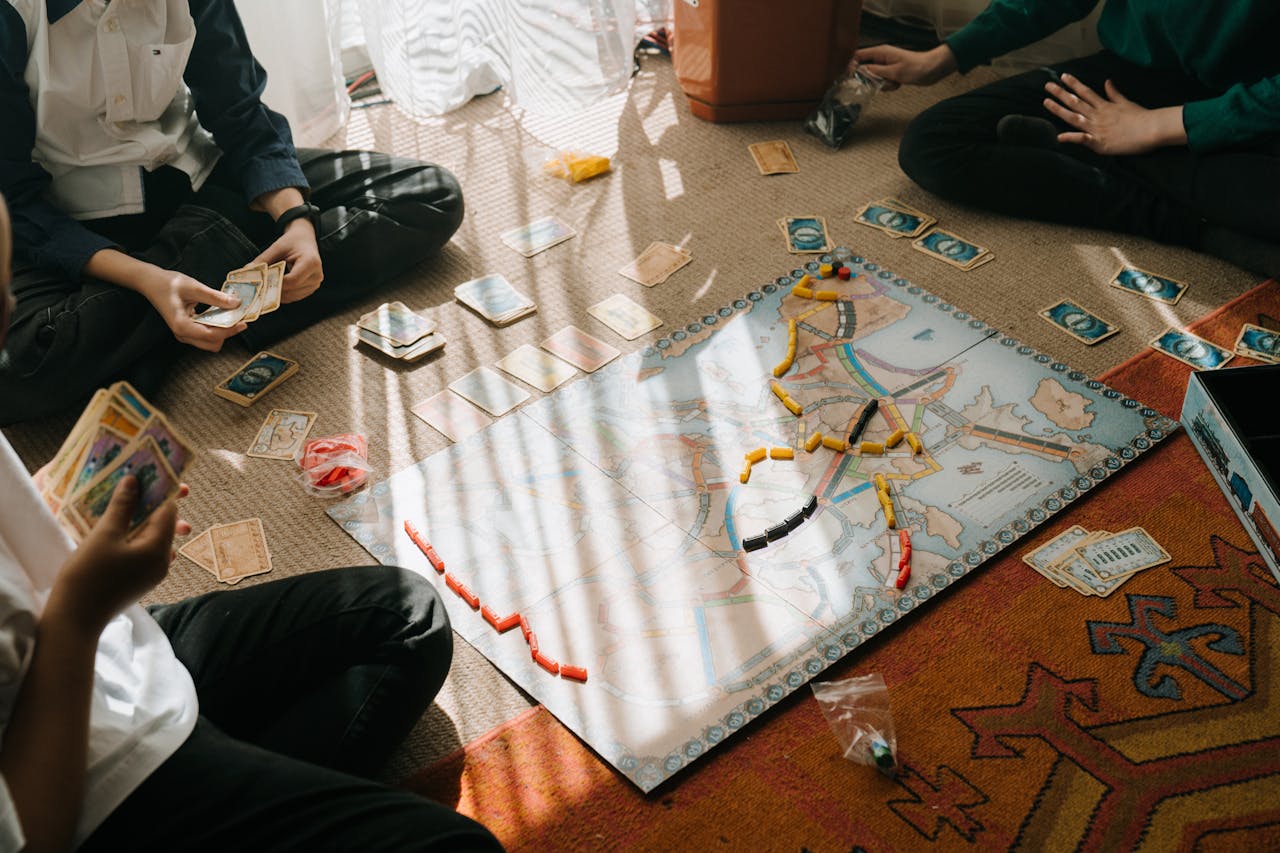 Three Persons in Black Pants Sitting on Floor Playing board Game